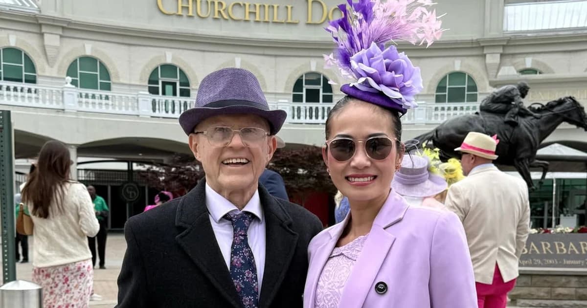 Bill Hajdu (the Firepig) and his companion in lavender and purple Derby attire standing in front of the Churchill Downs entrance, with the Barbaro statue visible in the background